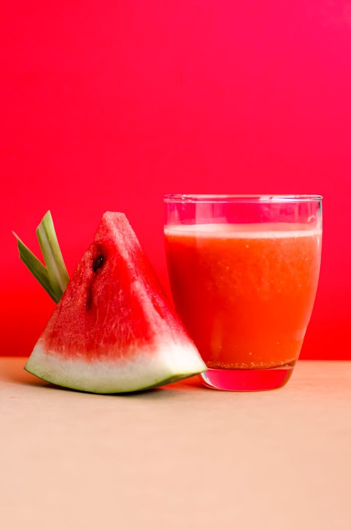 menu-03 Refreshing watermelon juice and slice against a vibrant red background, perfect for summer vibes.